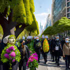 Colorful Bouquet-Wielding Group in Masks on Whimsical City Street