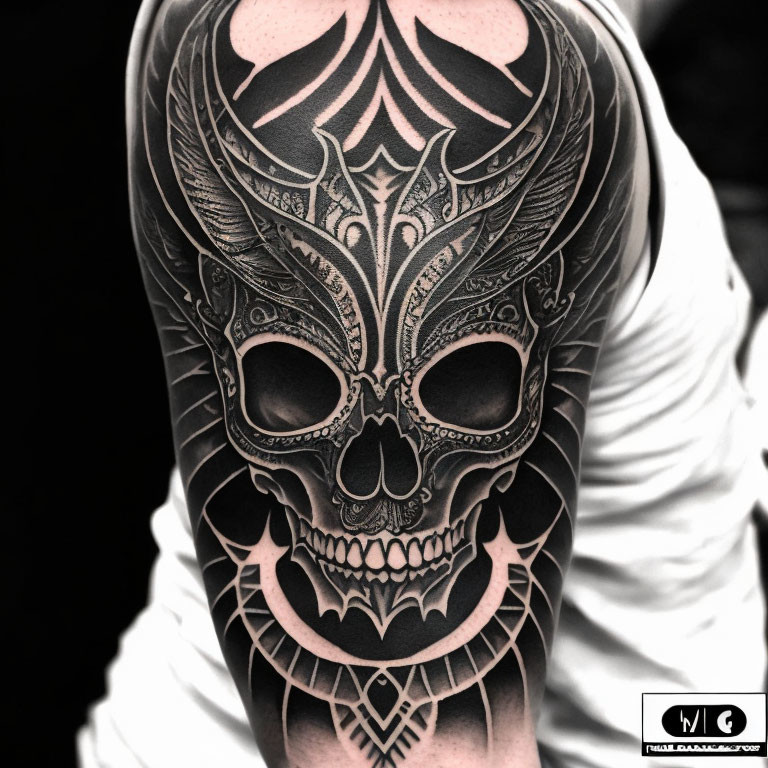 Detailed black and grey ornate skull tattoo on arm with intricate patterns