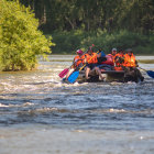 Group of People Rafting in Safety Gear on Rapid River