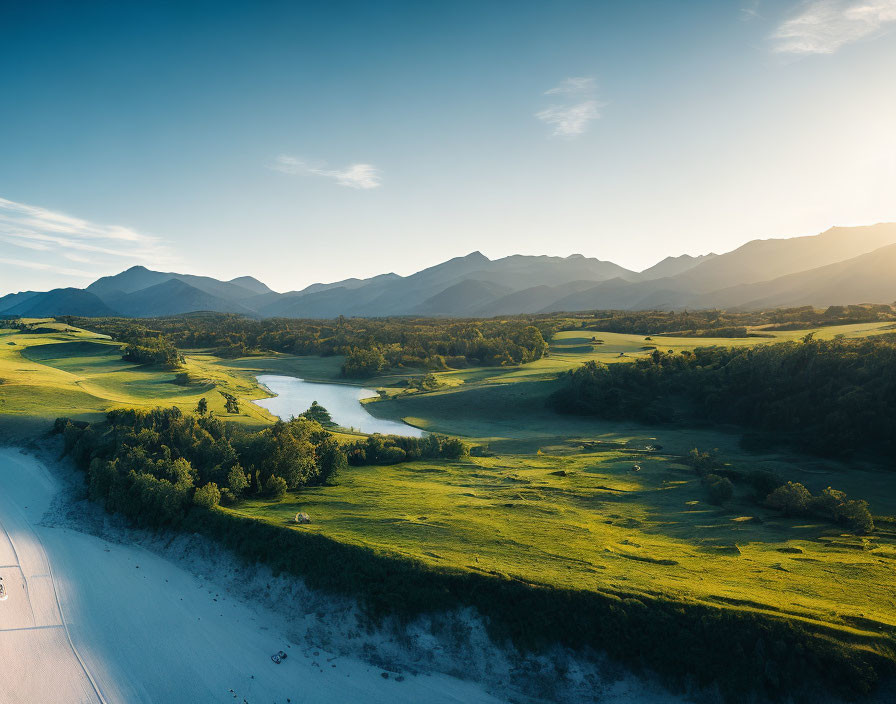 Tranquil landscape with winding river, green banks, hills, and mountains