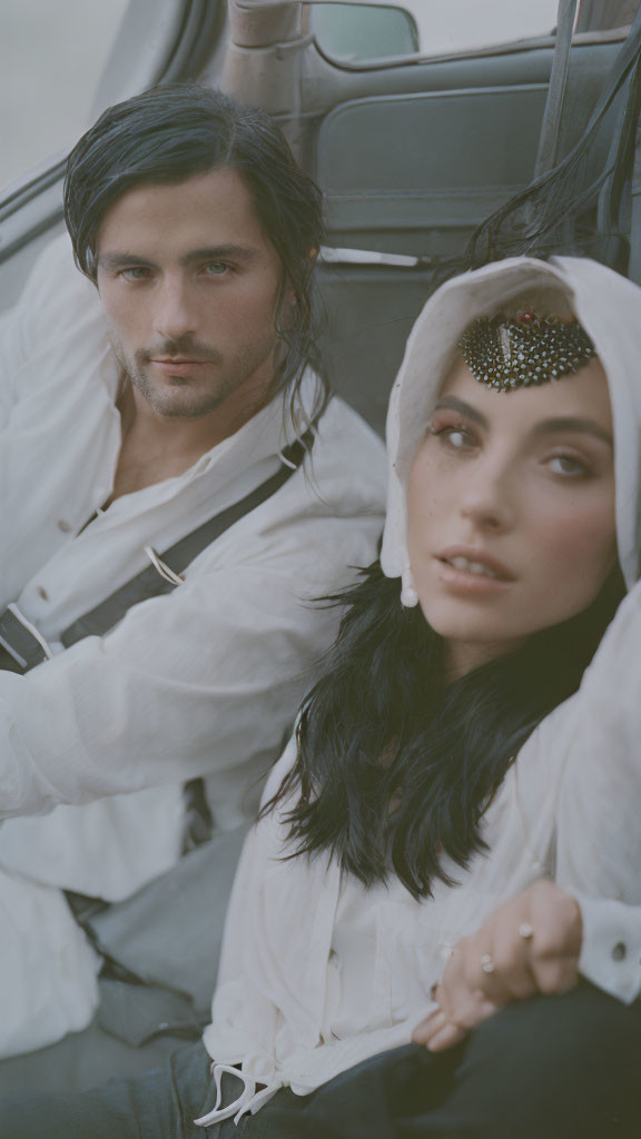 Vintage-inspired couple in white outfits with sparkle, posing in classic car