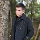 Dark-haired man in leather jacket and scarf in misty forest