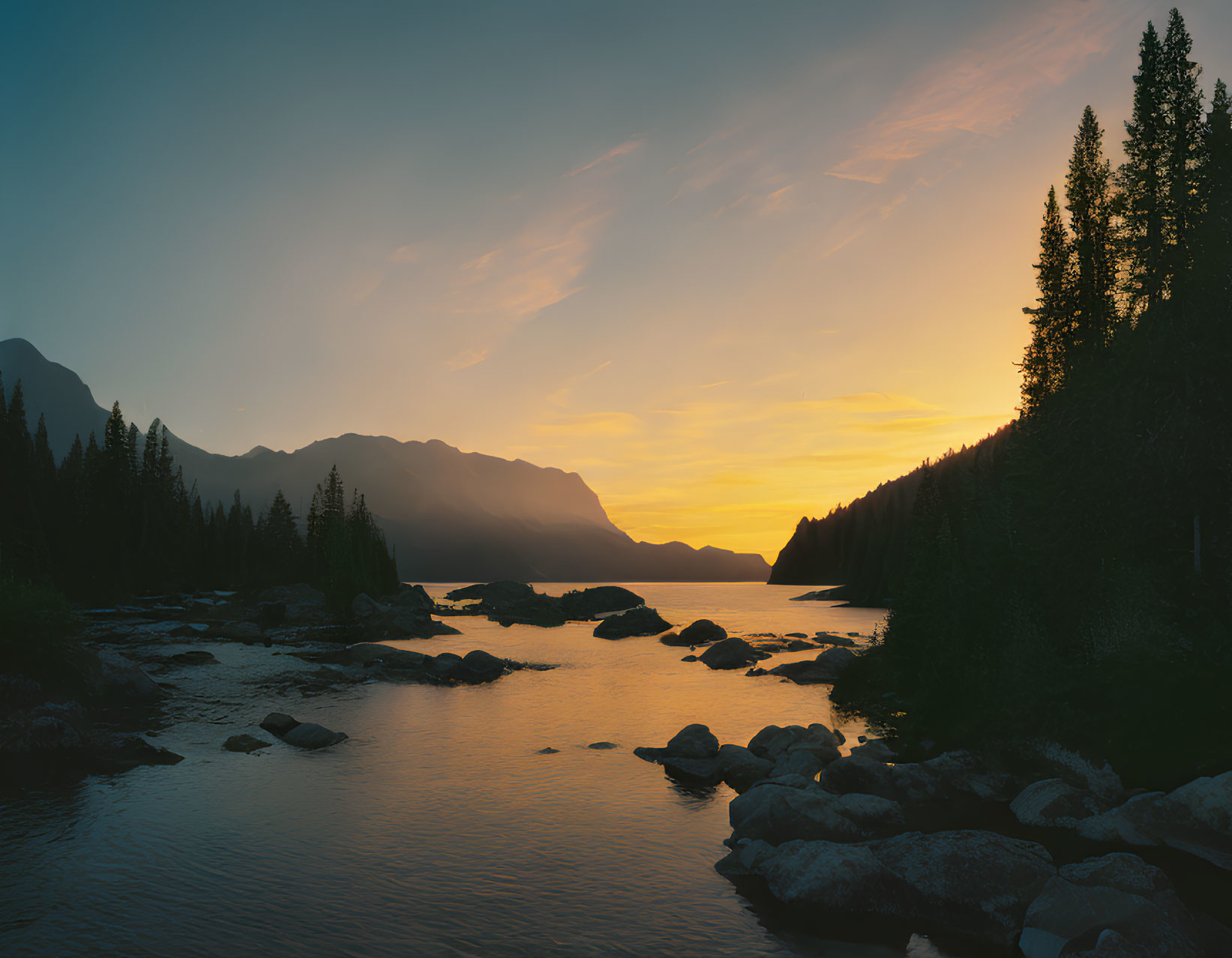 Scenic sunset over mountain landscape with forest and river.