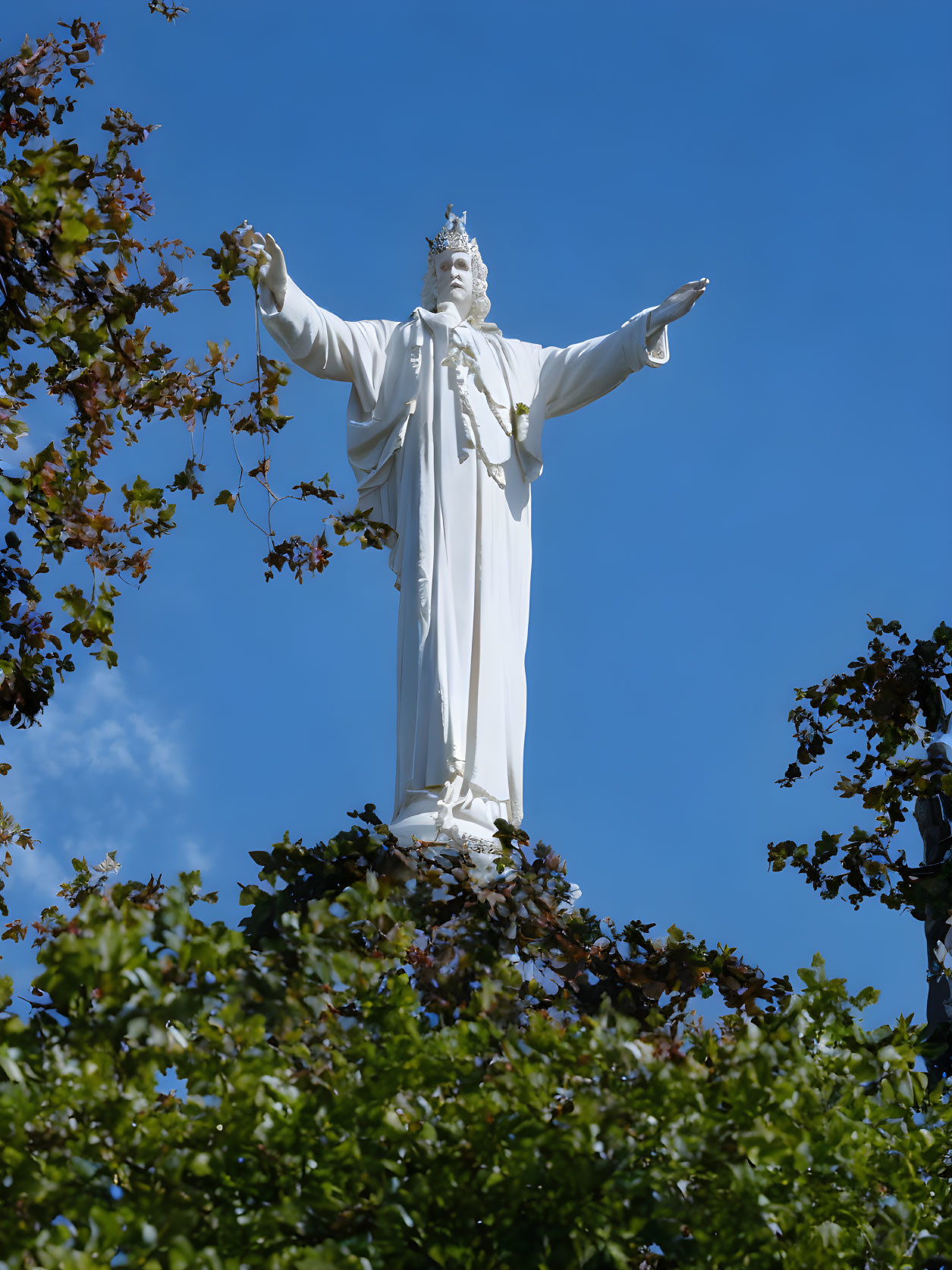 Tall white robed figure statue in nature landscape