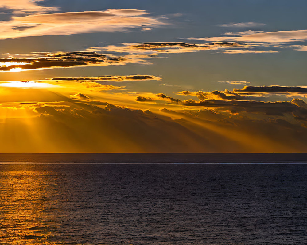 Vibrant sunset over ocean with sunbeams through clouds