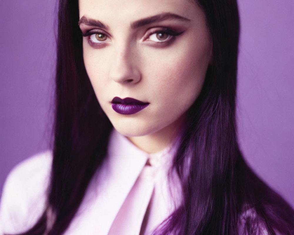 Dark-haired woman with purple lipstick in lilac shirt on purple background