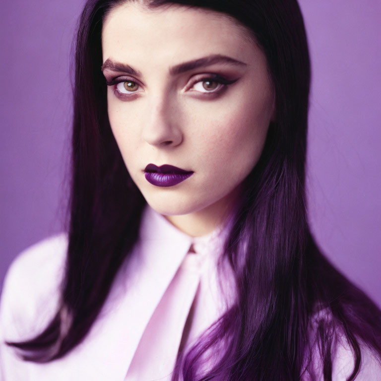 Dark-haired woman with purple lipstick in lilac shirt on purple background