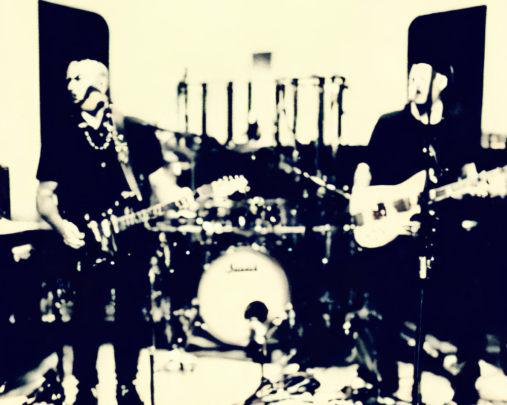 Blurred image of musicians with guitars and microphones, drum set in background