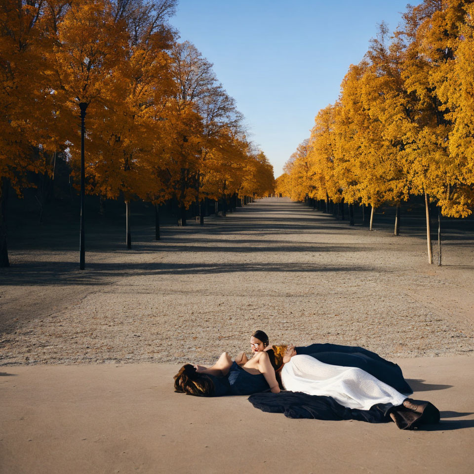 Woman in white dress lying on autumn path with golden trees and blue sky