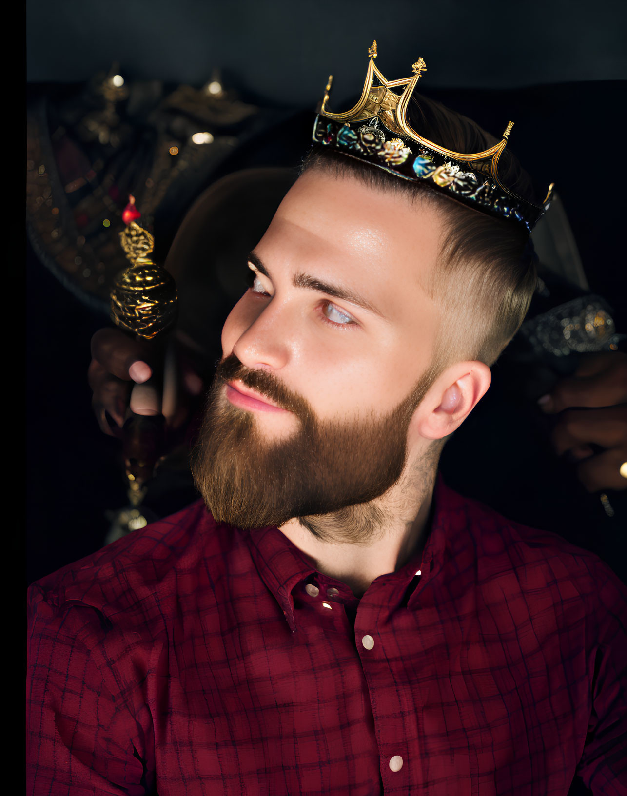 Bearded man in crown and armor holding scepter on red shirt background