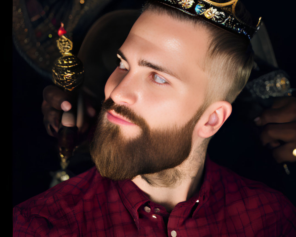 Bearded man in crown and armor holding scepter on red shirt background