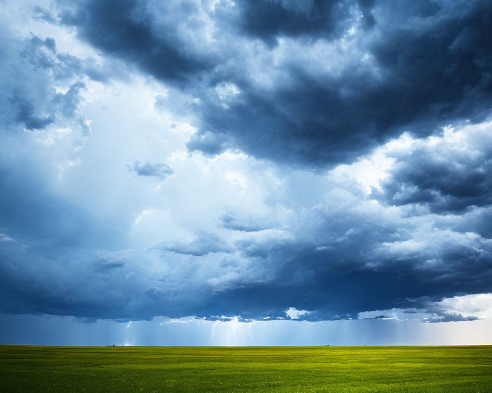 Dramatic landscape with dark storm clouds and sunbeams illuminating green field