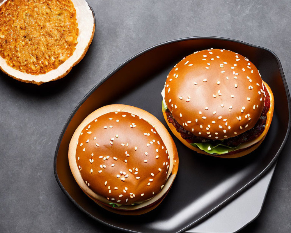 Two Sesame Bun Burgers with Lettuce and Patties on Black Plate