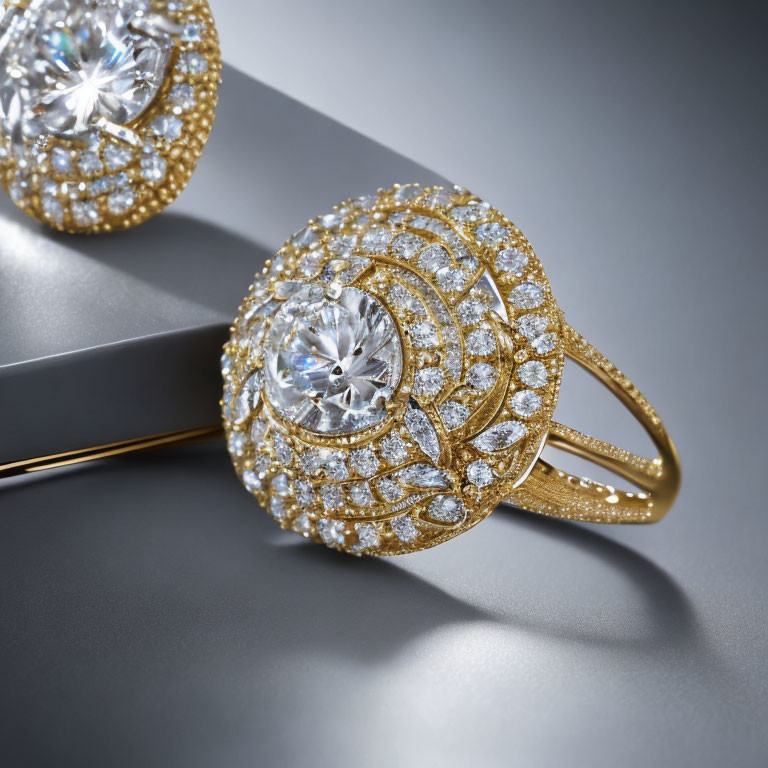 Luxury gold rings with intricate designs and embedded diamonds on reflective grey surface