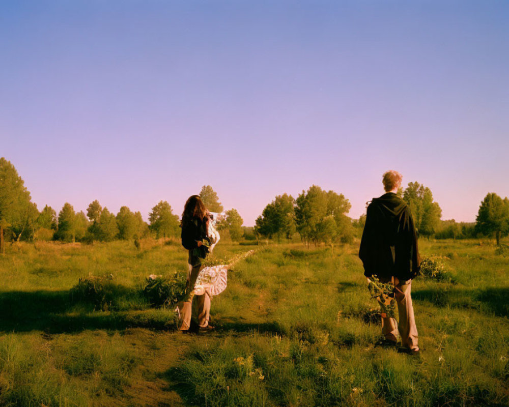 Lush Field with Two People Walking at Sunrise or Sunset