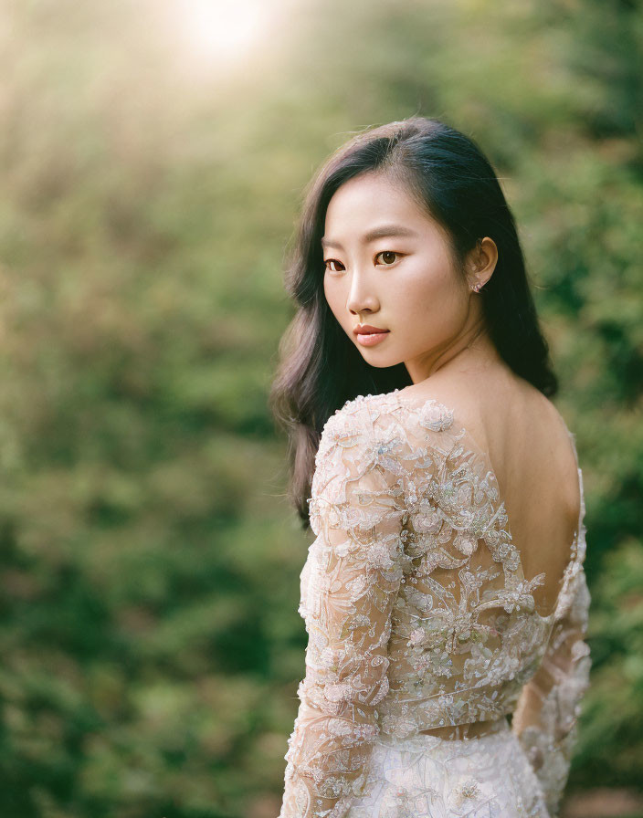 Elegant woman in lace dress against greenery backdrop