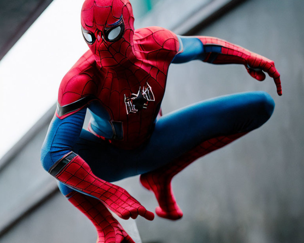 Person in Spider-Man costume crouching on concrete with buildings in background