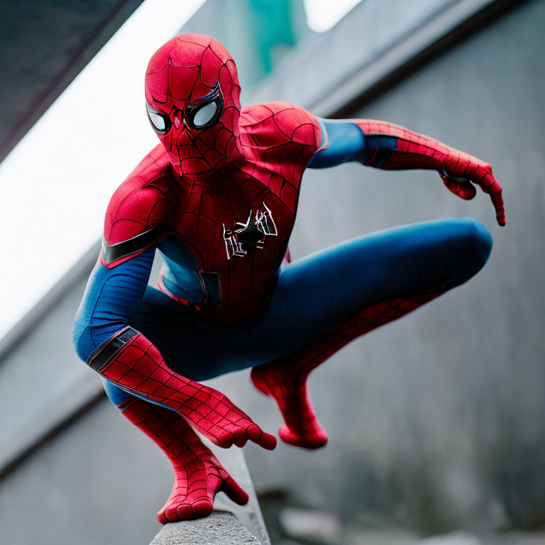 Person in Spider-Man costume crouching on concrete with buildings in background