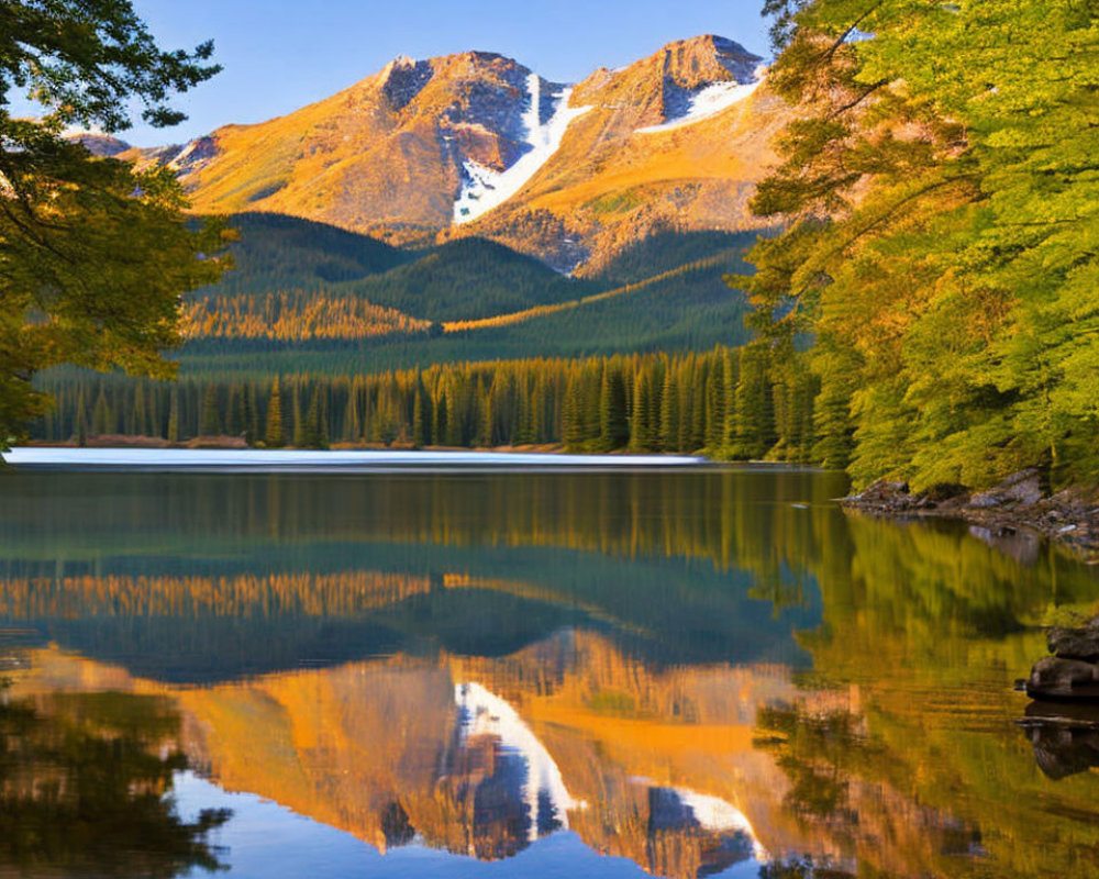 Tranquil lake mirroring autumn forest and mountain range