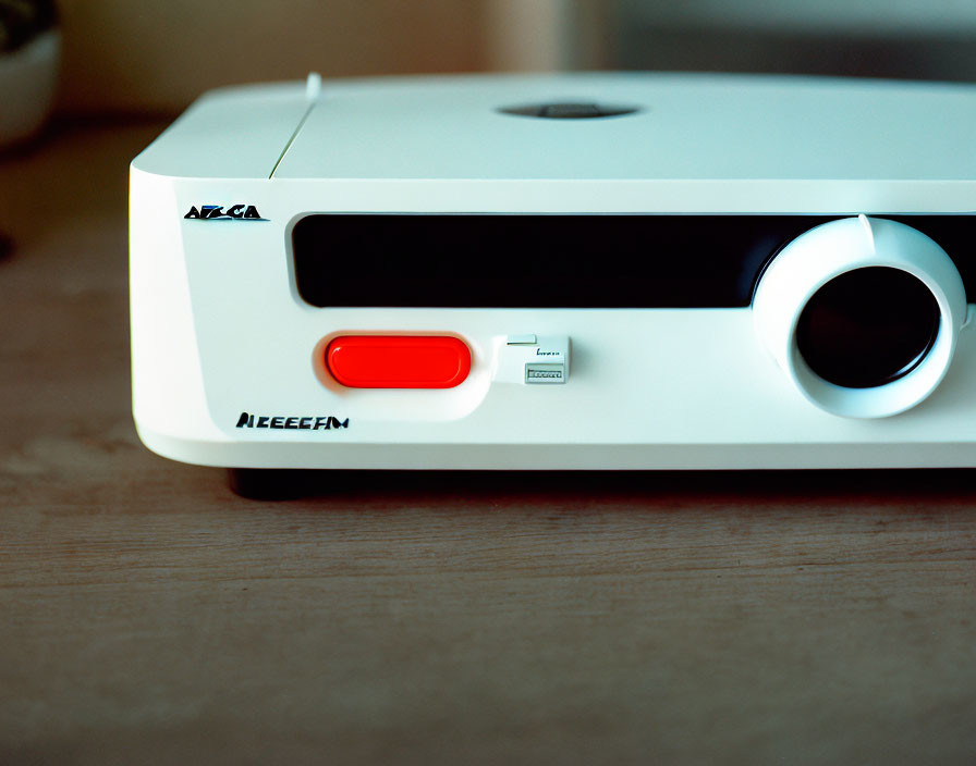 White projector with red power button and "NEEEFM" on wooden surface