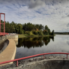 Tranquil painting of red suspension bridge over calm river