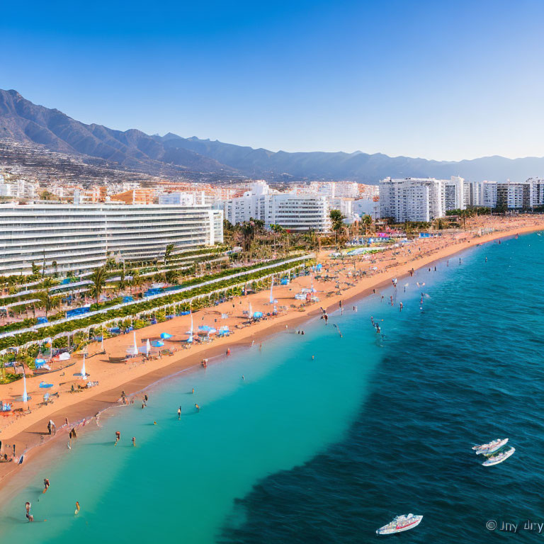 Tropical beach scene with umbrellas, palm trees, cityscape, mountains, and boats