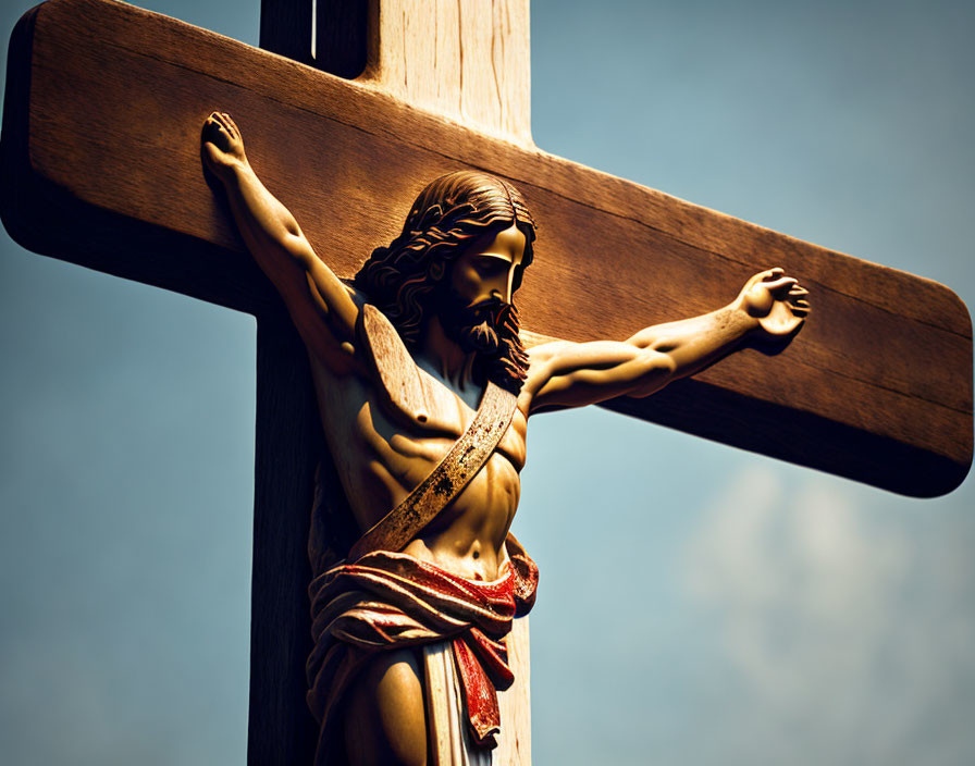 Wooden Crucifix with Sculpted Jesus Figure Against Blue Sky