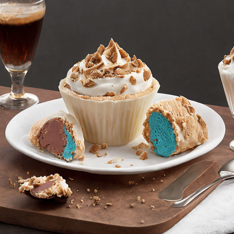 Half-eaten cupcake with blue center and crumbled toppings on plate with spoon