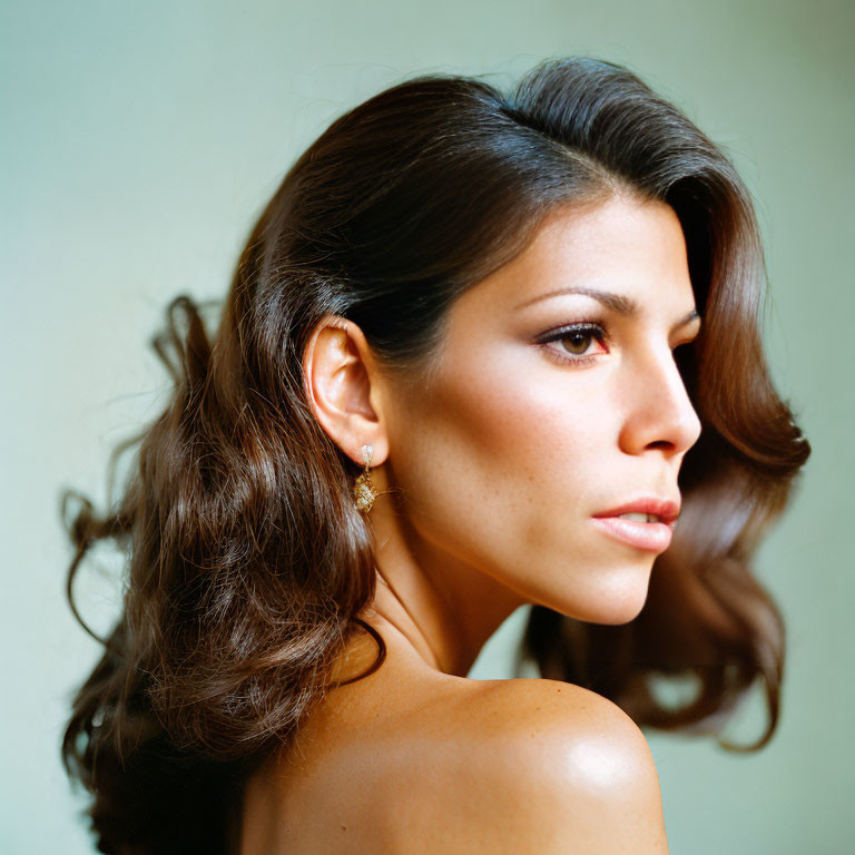 Brown-haired woman with subtle makeup in profile against soft background