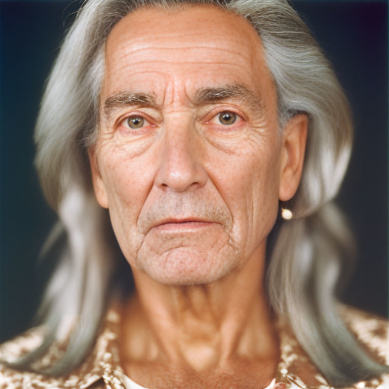 Elderly person with long grey hair and deep wrinkles in golden patterned shirt