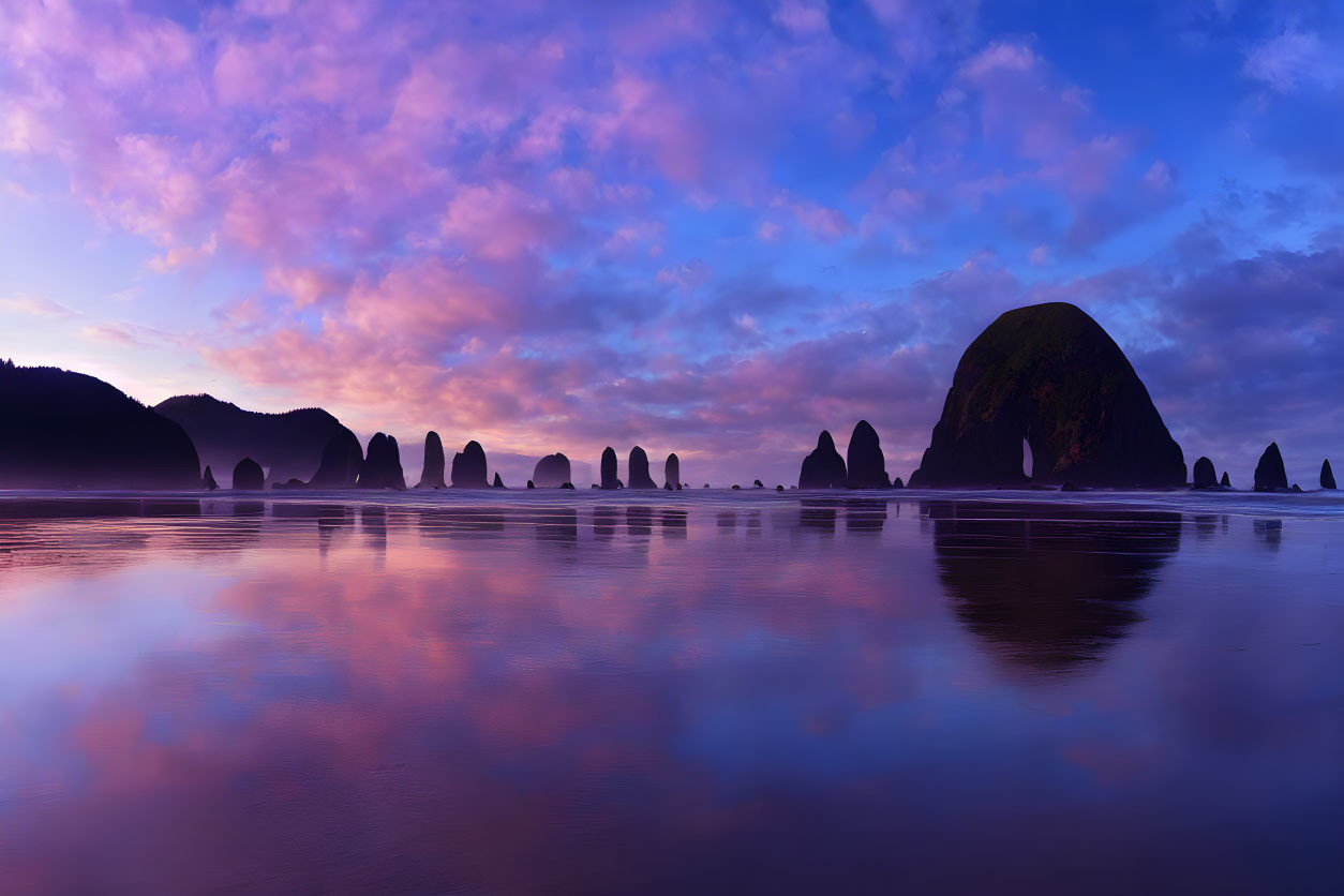 Tranquil beach at dusk: Purple skies, wet sand, sea stack silhouettes