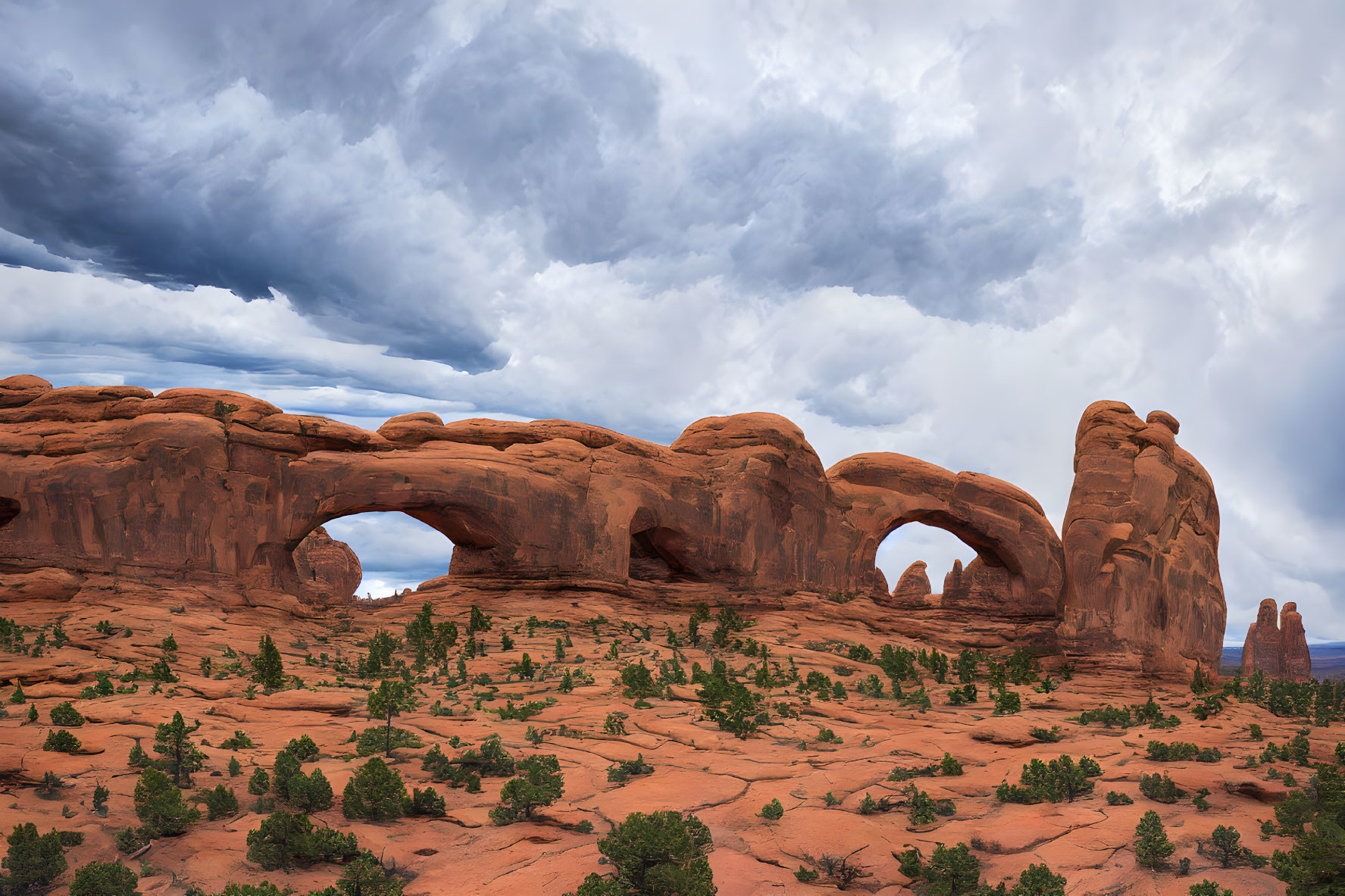 Iconic red sandstone arches under dramatic cloudy sky in Arches National Park