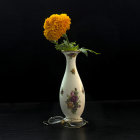 Yellow rose in white vase on black background with fallen petals and leaves