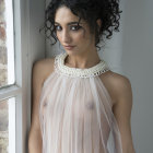 Tousled hair woman in white high-neck outfit with ornate necklace