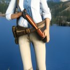 Female character in western attire with cowboy hat, rifle, blue shirt, leather belt, green pants,