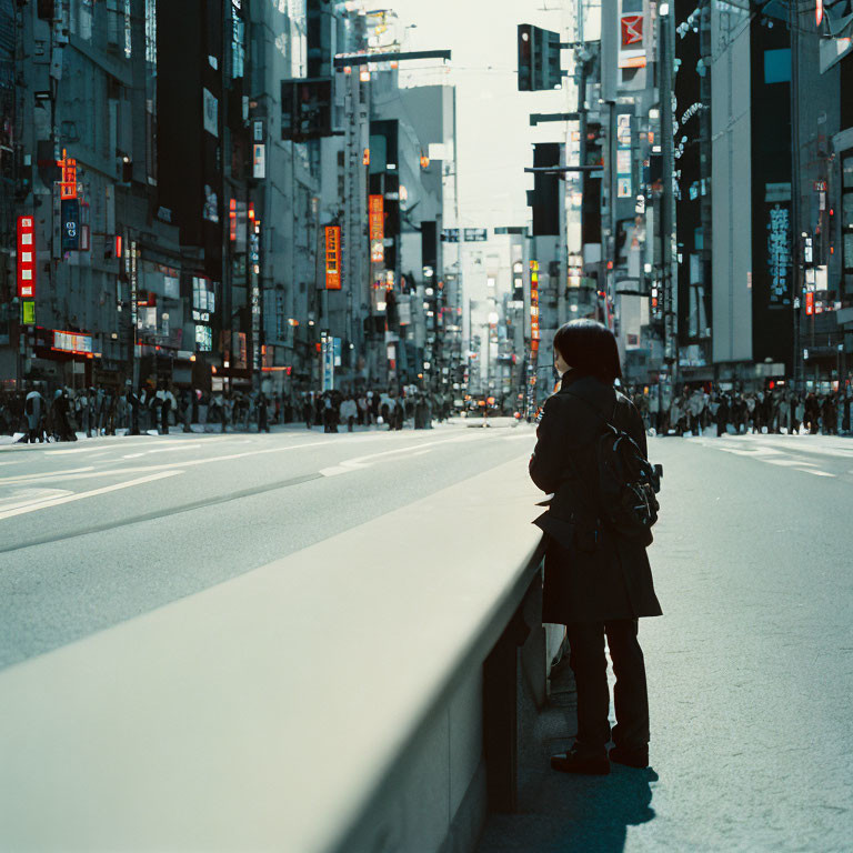 Solitary figure at urban crosswalk with city billboards and pedestrians