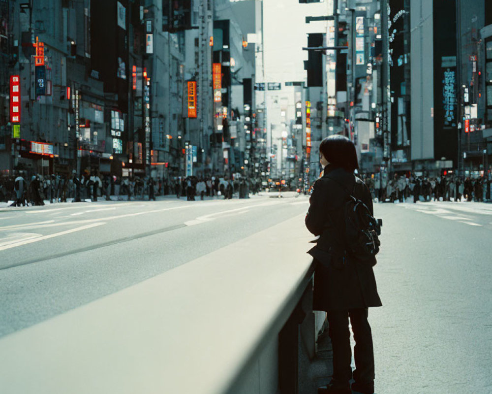 Solitary figure at urban crosswalk with city billboards and pedestrians