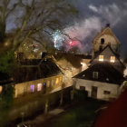 Charming village scene: thatched cottages, cherry trees, lanterns, distant tower