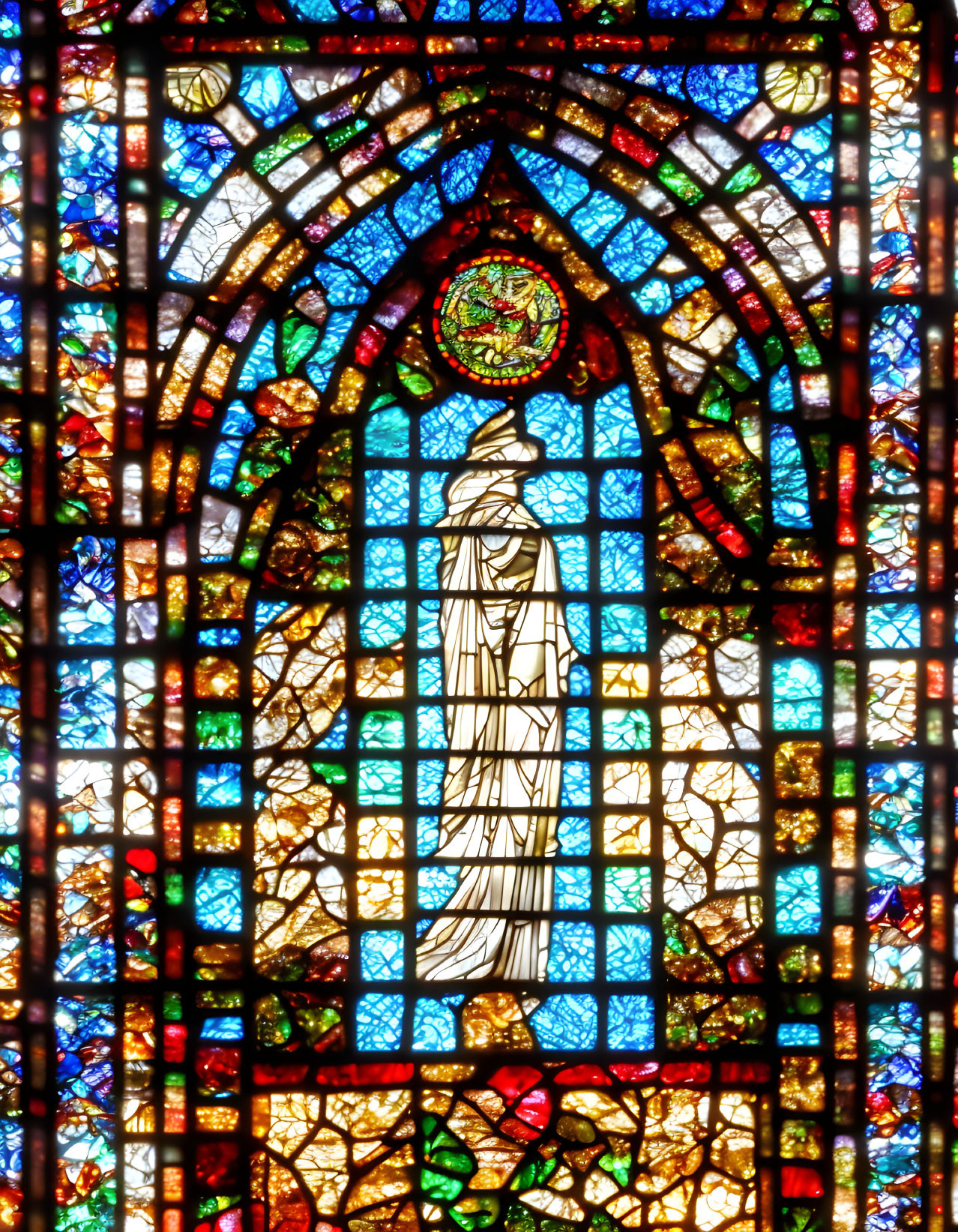 Colorful Stained Glass Window Featuring Robed Figure & Intricate Patterns