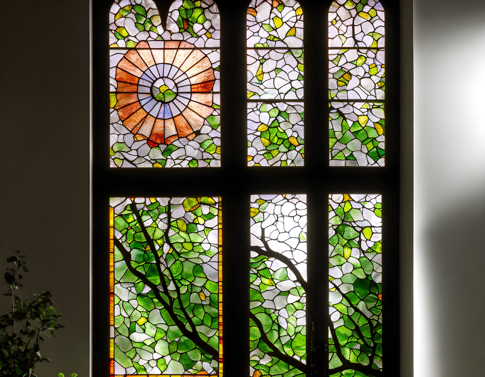 Vibrant floral stained glass window with green foliage on white wall