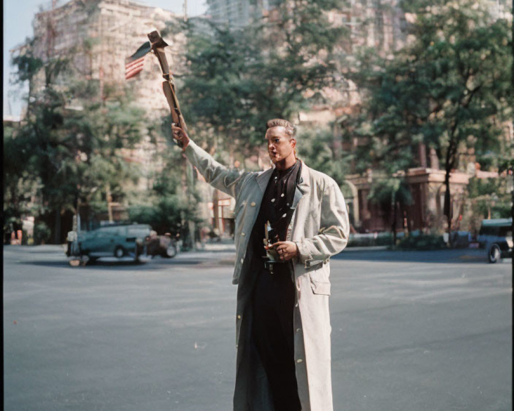 Person holding trophy and model airplane in open space with trees and city buildings.