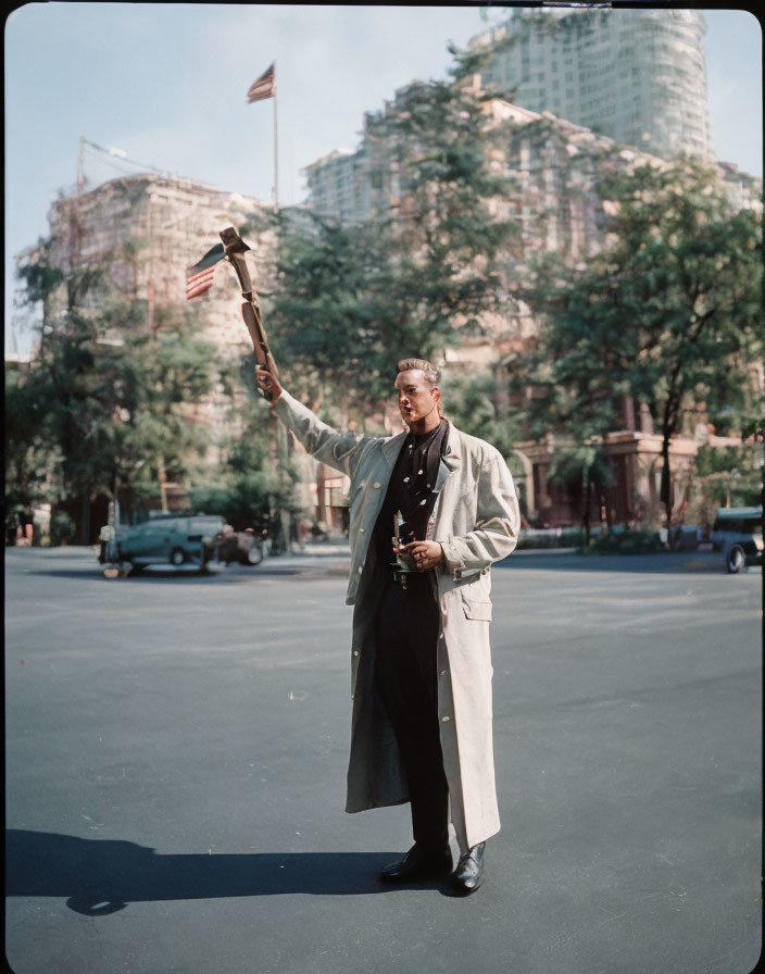 Person holding trophy and model airplane in open space with trees and city buildings.