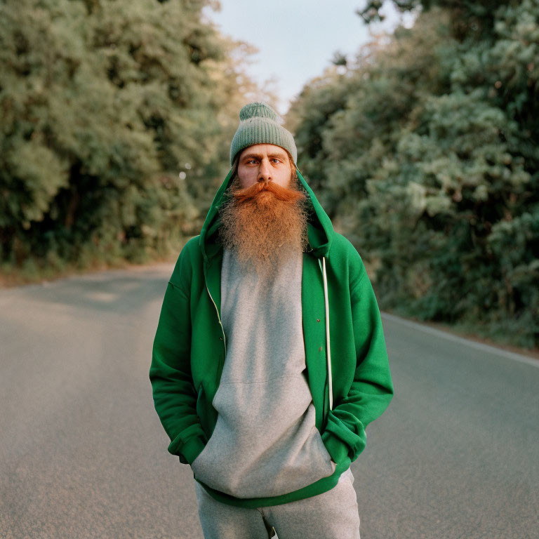 Bearded Person in Green Beanie and Hoodie on Road with Trees