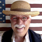 Elderly man in golden armor with white beard and helmet before American flag