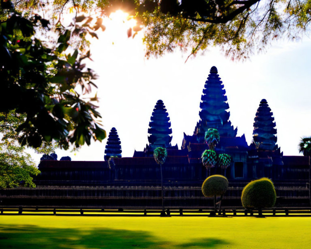 Sunlight through trees on Angkor Wat temple spires and green lawn