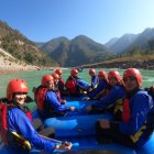 People in life jackets and helmets on raft in mountain lake