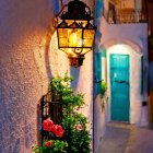 Vintage lamp post glowing at dusk with blooming flowers and ivy by old window