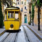 Vintage Yellow Tram on Cobblestone Tracks in Colorful Street