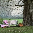 Plush blue sofa under blooming tree in serene fantasy setting