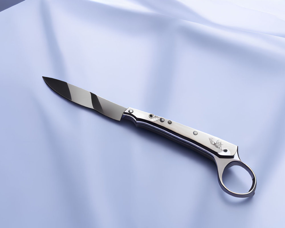 Round Finger Hole Folding Knife with Decorated Handle on Blue Satin Fabric